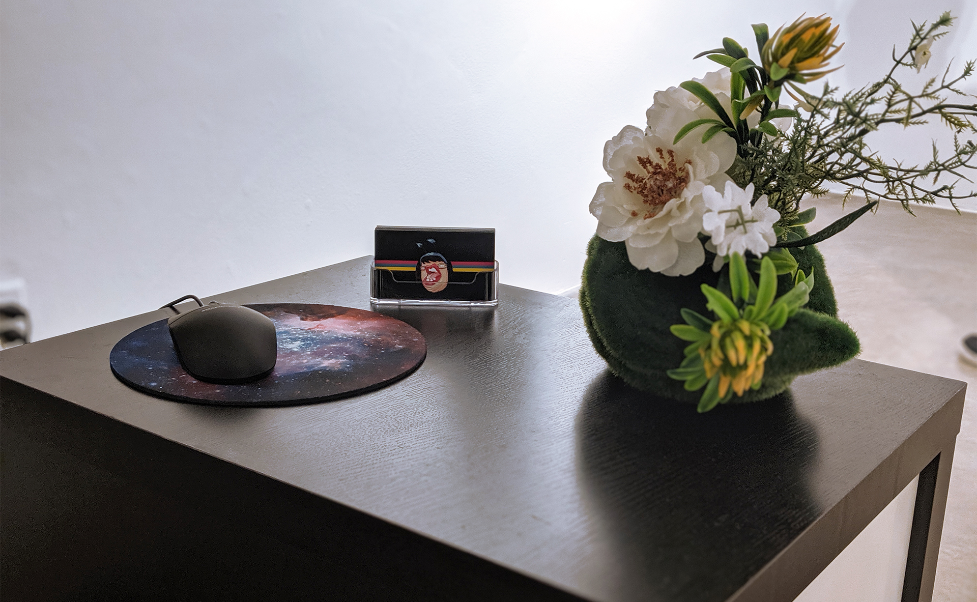 Gallery installation detail showing mouse, interface controls, and decorative elements on display table.